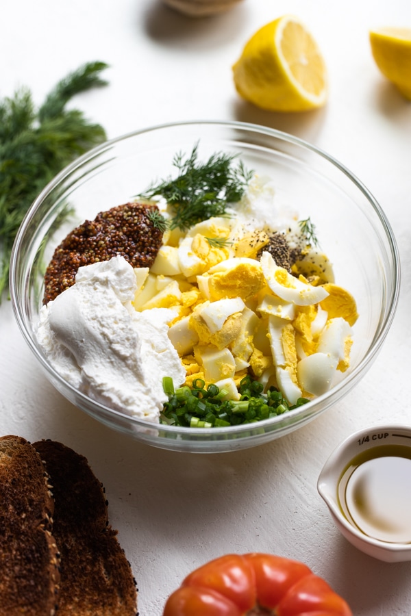 all of the ingredients to make an egg salad in a large glass mixing bowl