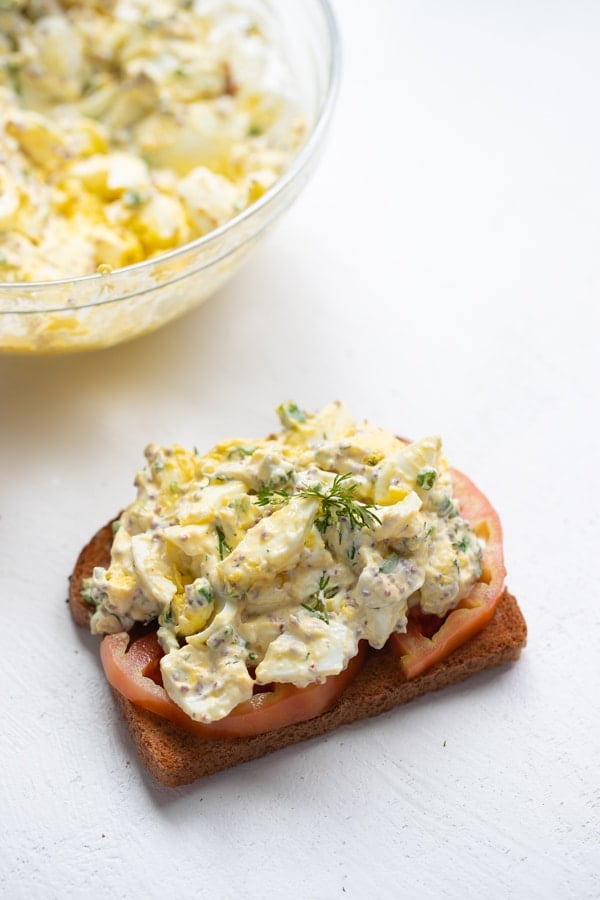 egg salad sandwich on wheat bread with baby kale, Dijon and heirloom tomatoes