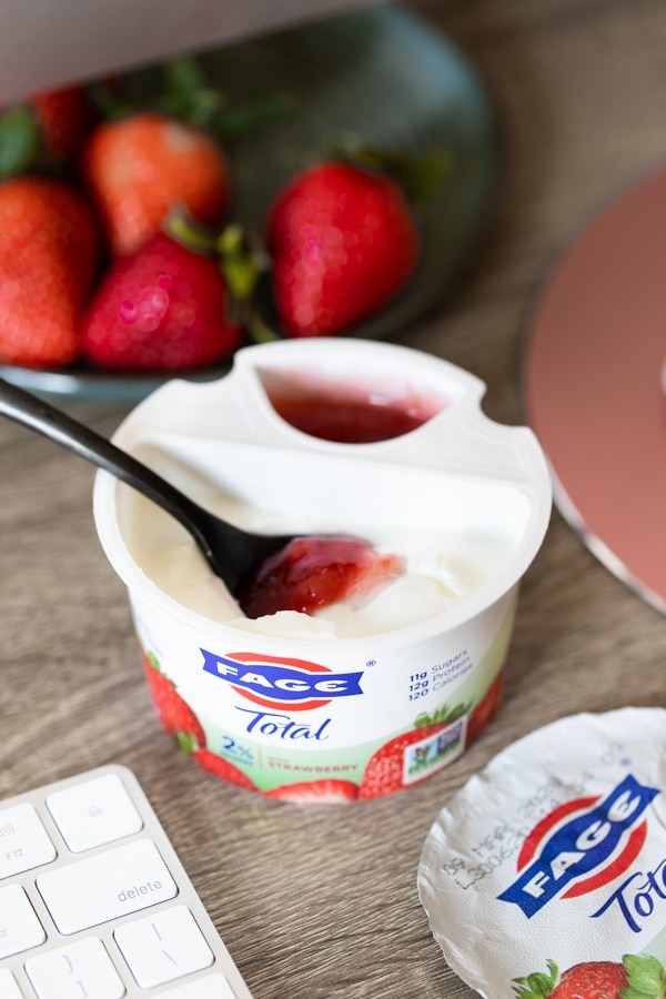 yogurt on a desk with a spoon in the yogurt