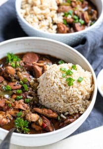 a white bowl filled with chicken and sausage gumbo topped with brown rice