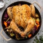 whole chicken roasted with roasted vegetables in a black cast iron dutch oven