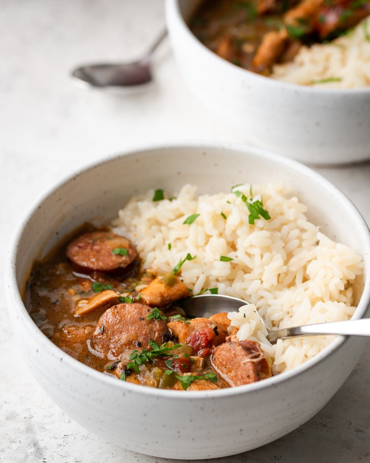 Gumbo in a white bowl garnished with parsley. 