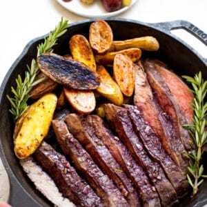 baked flank steak and fingerling potatoes in a cast iron skillet