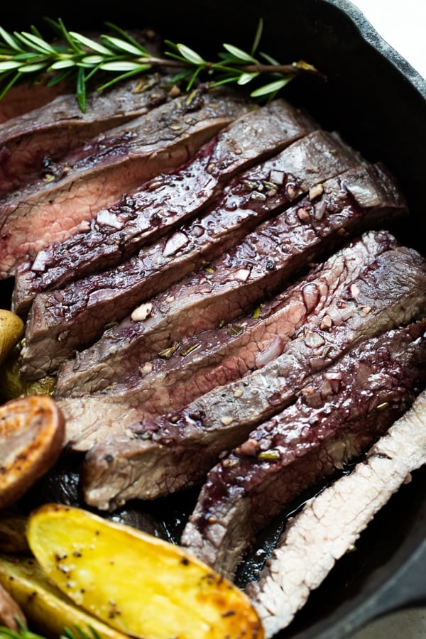 flank steak with a red wine marinade on top in a cast iron pan