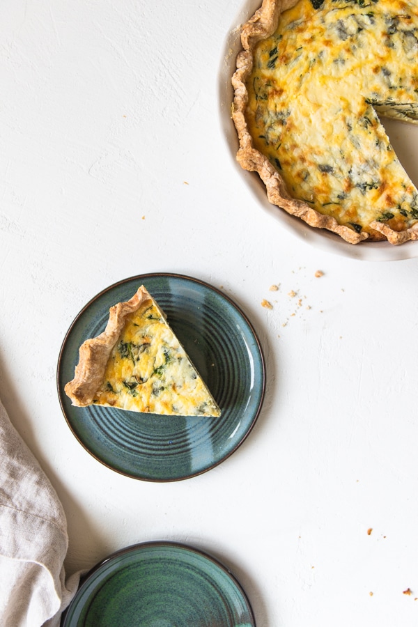 een plakje quiche Florentine op een blauwe plaat