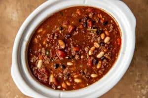 spicy chili in a white slow cooker.