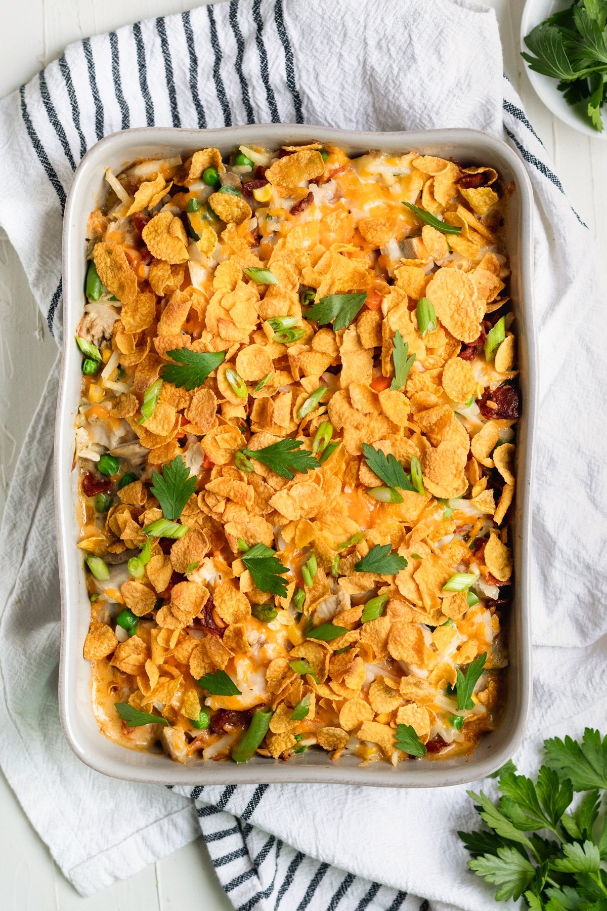 casserole in a casserole dish made with chicken and hash browns topped with cornflakes and fresh parsley