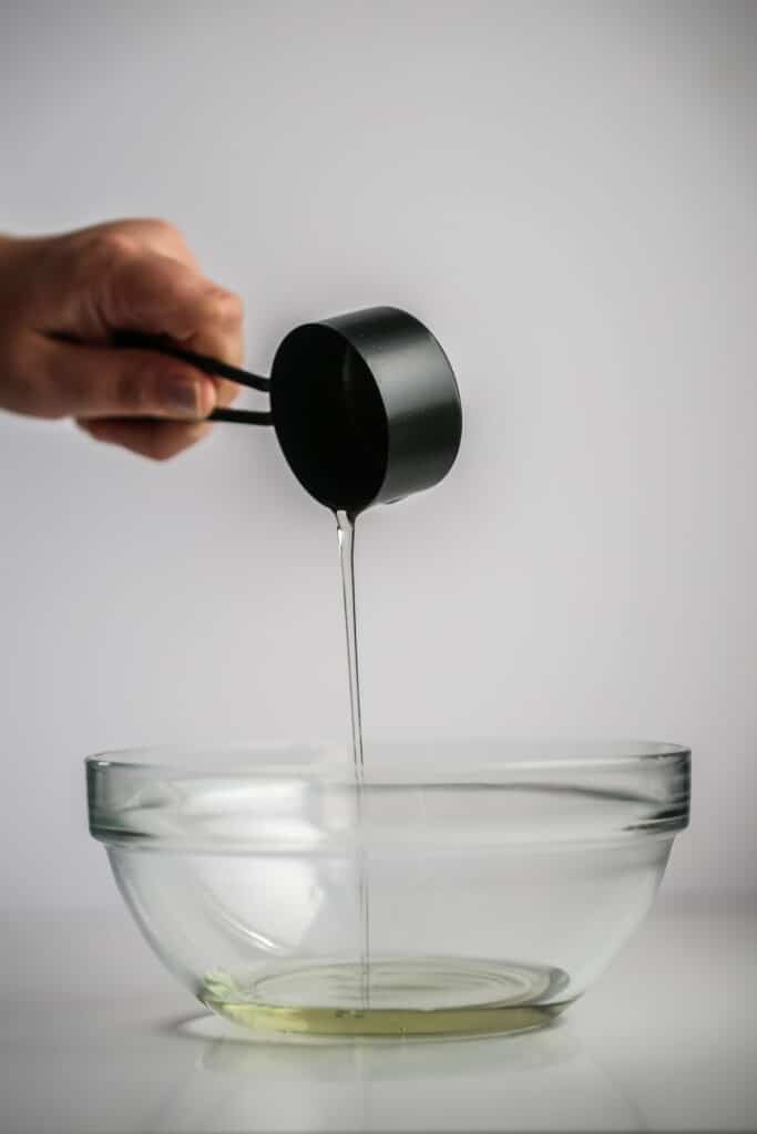 A person holding a wine a measuring cup filled with soybean oil