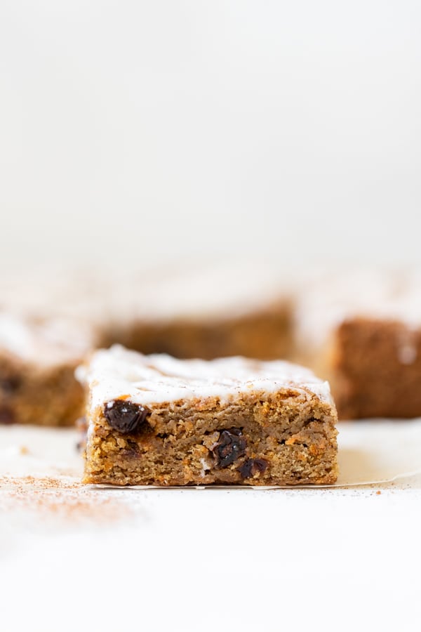 carrot cake bars with icing on parchment paper