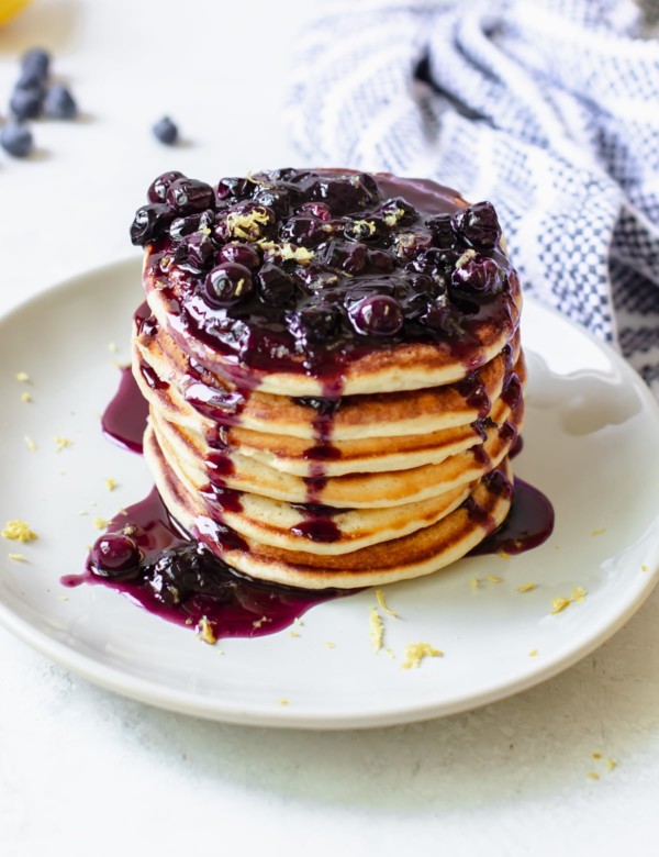 a stack of pancakes on a plate with blueberry syrup on top
