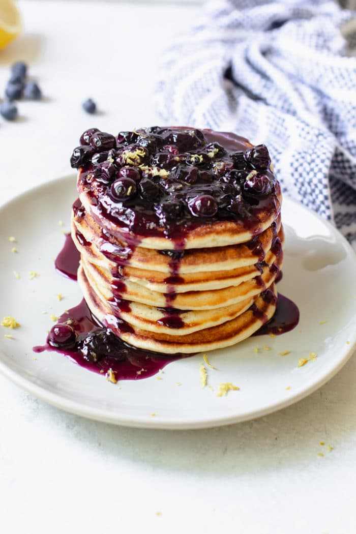 a stack of pancakes on a plate with blueberry syrup on top