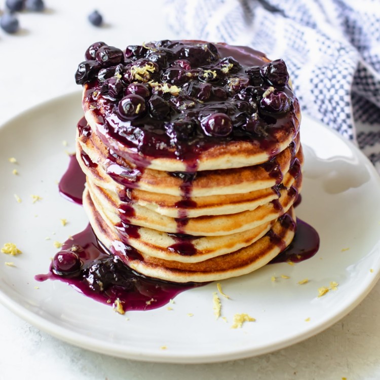 a stack of pancakes on a plate with blueberry syrup on top