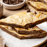 Three coffee cookie bars stacked on top of each other on plate.