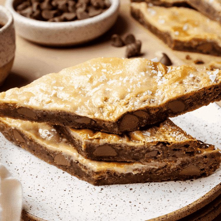 Three coffee cookie bars stacked on top of each other on plate.
