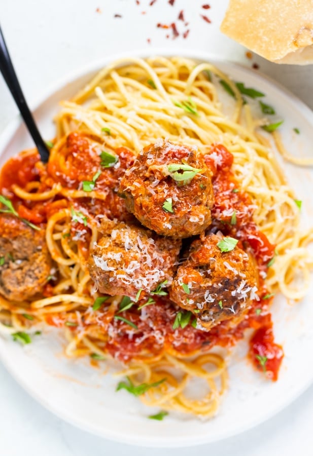 spaghetti and beef meatballs with parmesan cheese and parsley on top