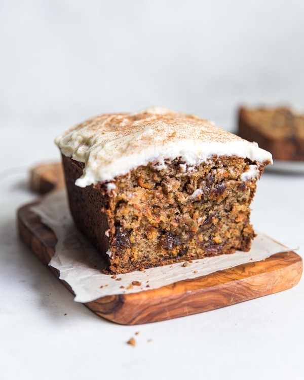 A piece of carrot cake sitting on top of a wood cutting board