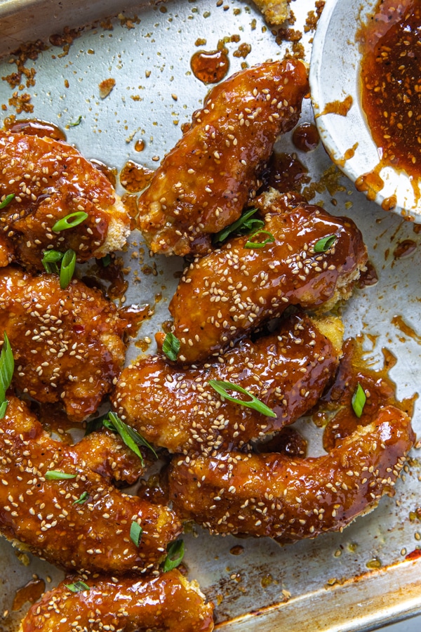 sesame chicken on a sheet pan with sesame seeds and green onions on top