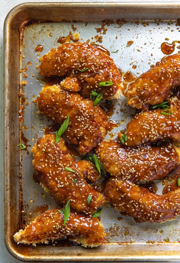 sesame chicken on a sheet pan with sesame seeds and green onions on top