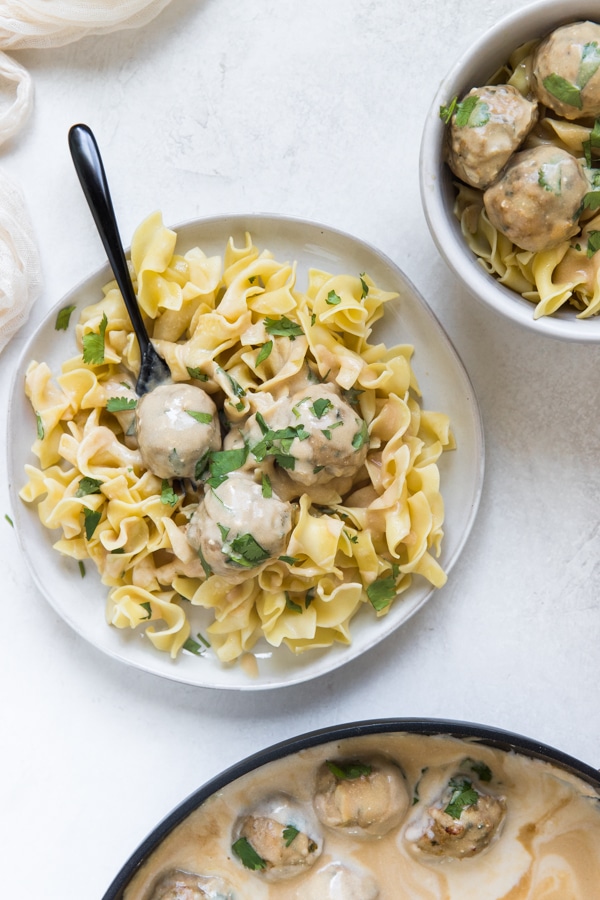 Swedish Meatballs in gravy on a white plate with wide egg noodles
