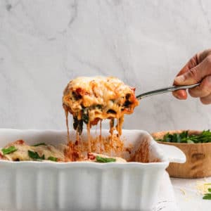 cheesy spinach ricotta rolled up into a lasagna noodle covered in red sauce