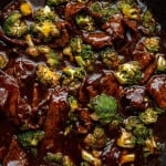 Close-up of beef and broccoli stir-fry in a dark sauce inside a skillet, showing tender beef slices and bright green broccoli coated in glossy sauce.