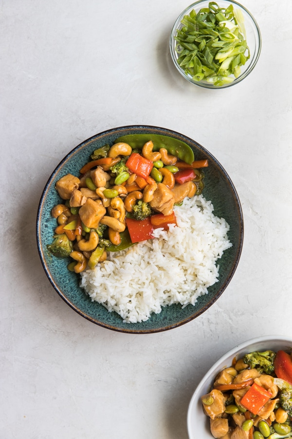 cashew chicken stir fry in a blue bowl with white rice