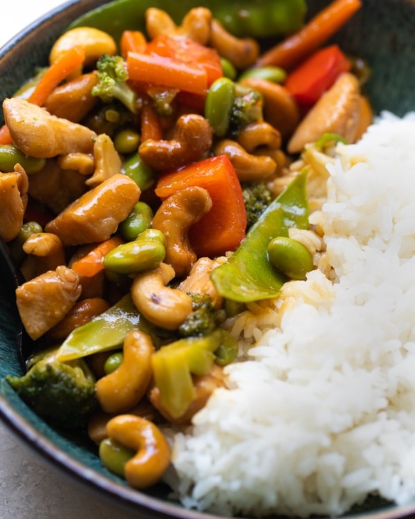 cashew chicken stir fry in a blue bowl with white rice