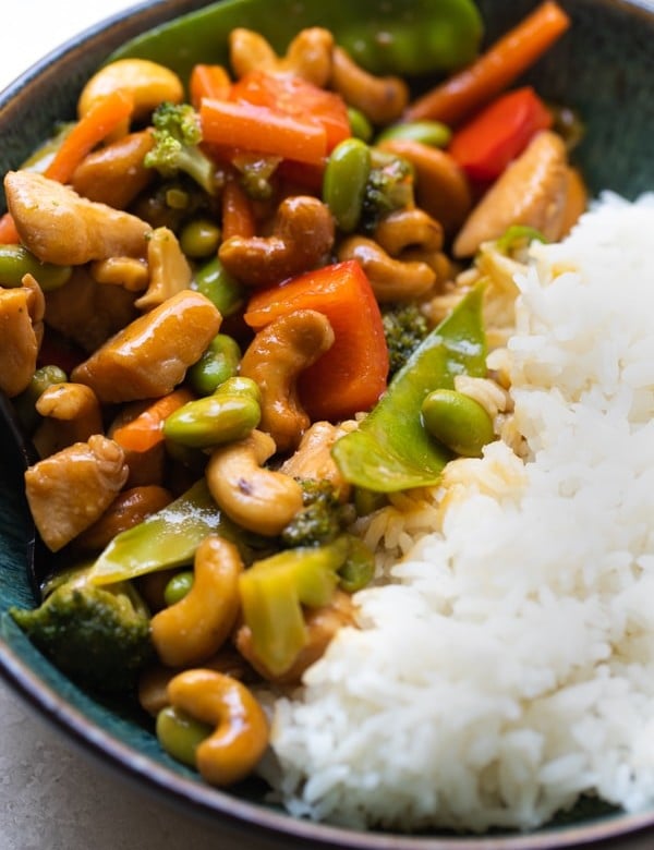 cashew chicken stir fry in a blue bowl with white rice