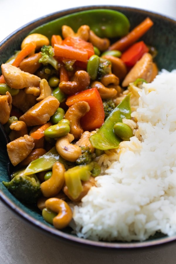 cashew chicken stir fry in a blue bowl with white rice