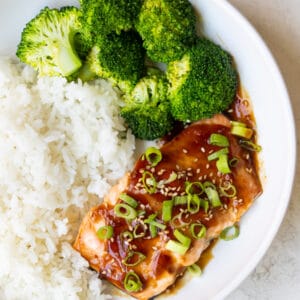 teriyaki glazed salmon in a white bowl with rice and broccoli