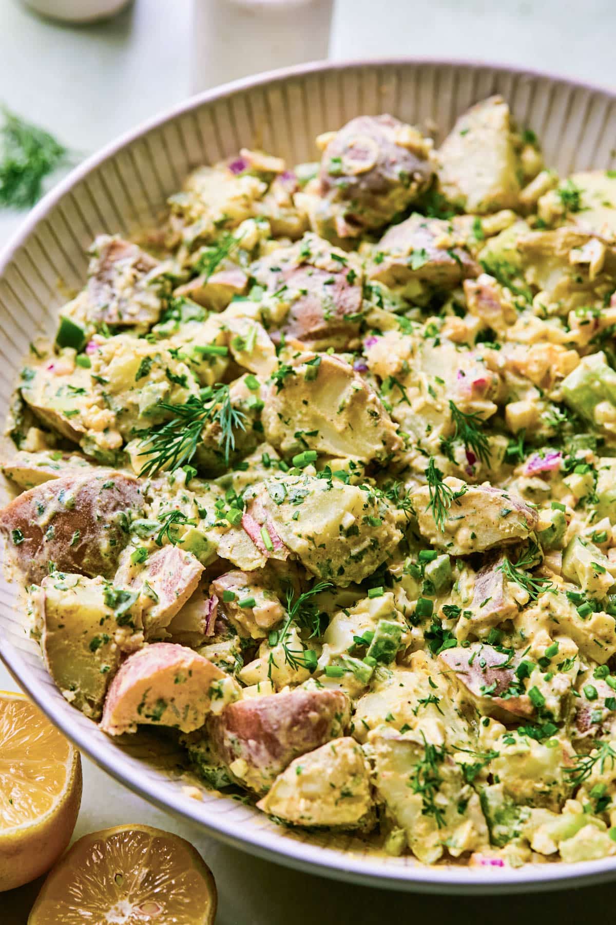 Creamy red potato salad with fresh dill and parsley in a large bowl.