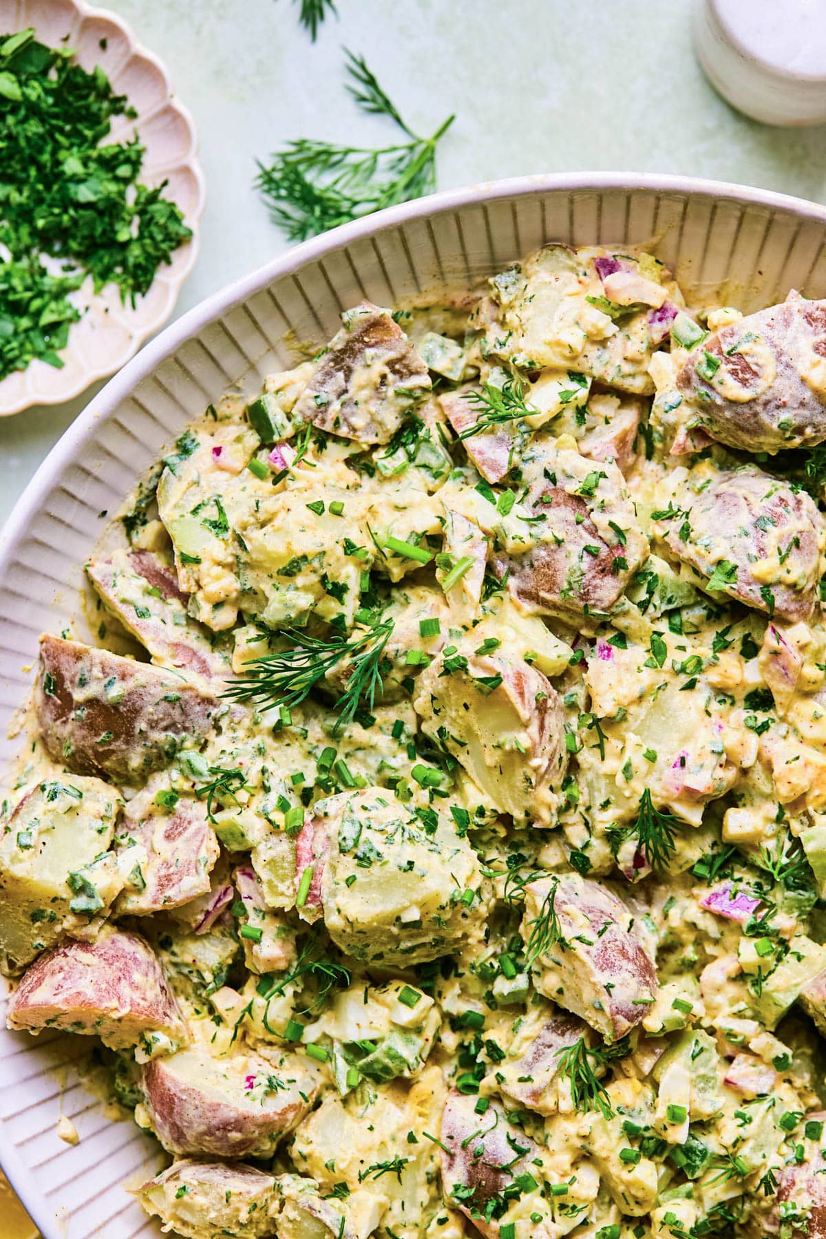 Salad of red potatoes, creamy dressing, chopped veggies, and fresh herbs.