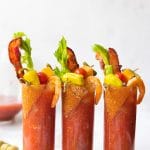 spicy bloody marys in glasses with bacon and celery