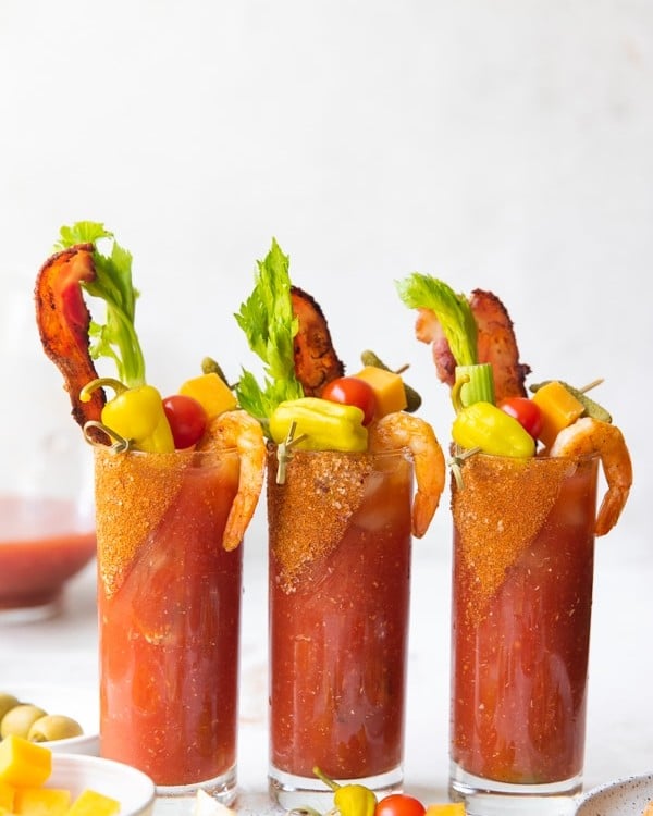 spicy bloody marys in glasses with bacon and celery
