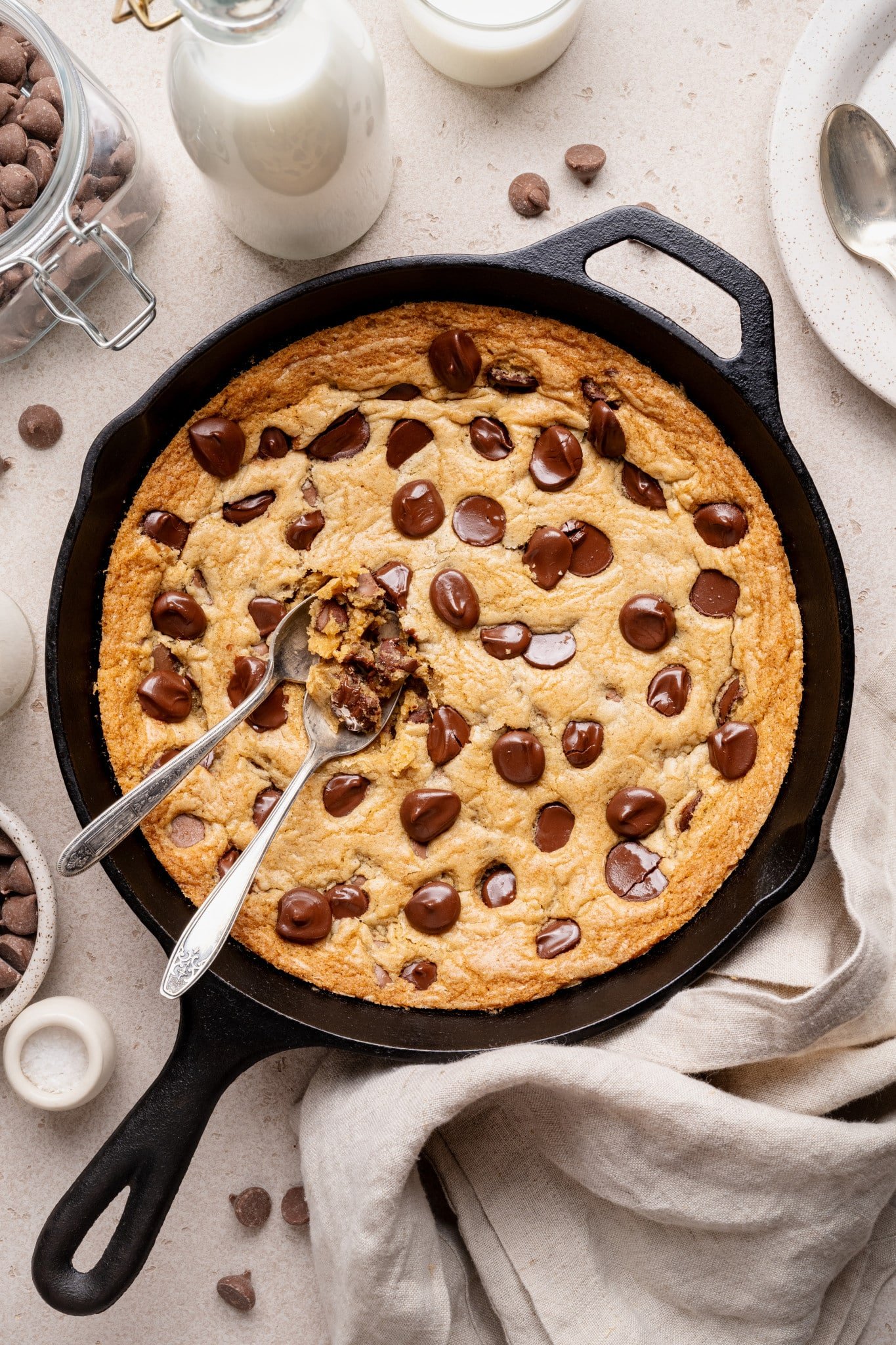 Cast iron skillet cookie baked in cast iron with two spoons digging in.