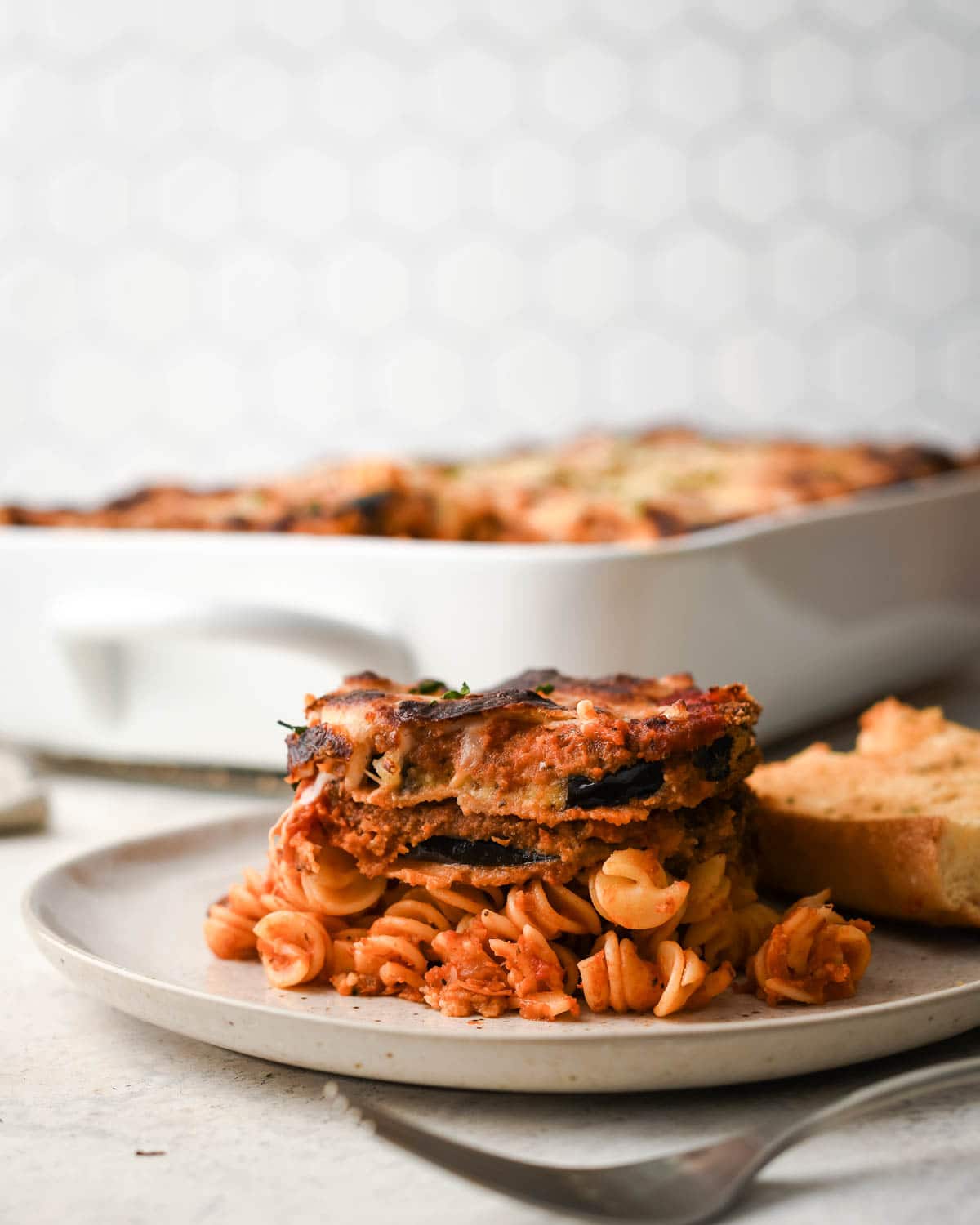 eggplant on a white speckled plate with pasta and red sauce