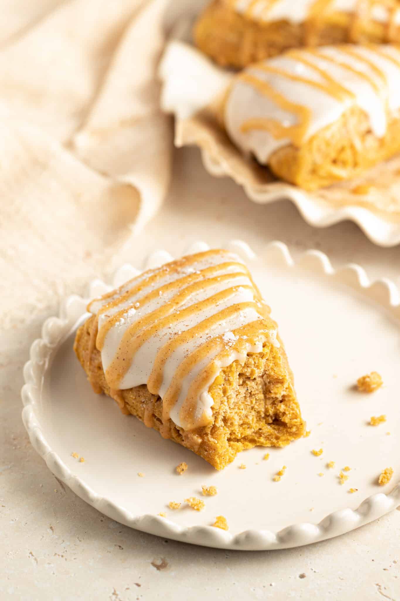 a pumpkin scone on a plate with a bite taken from it. 