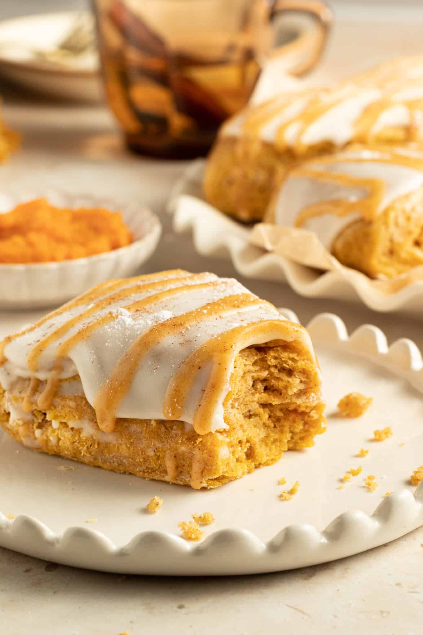 pumpkin scone on a white plate with a bite taken from it. 