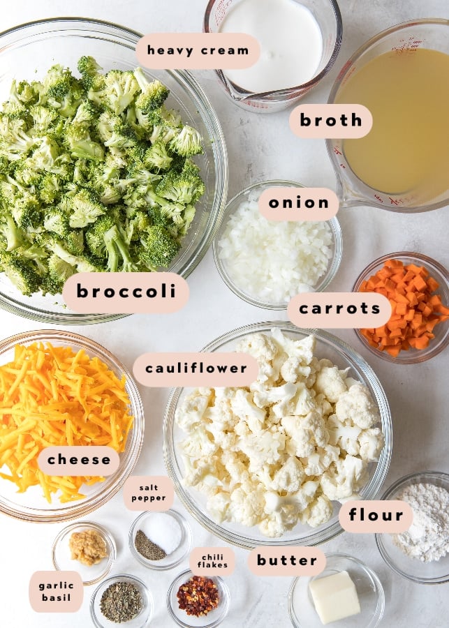 bowls and measuring cups featuring the ingredients to make broccoli cauliflower soup