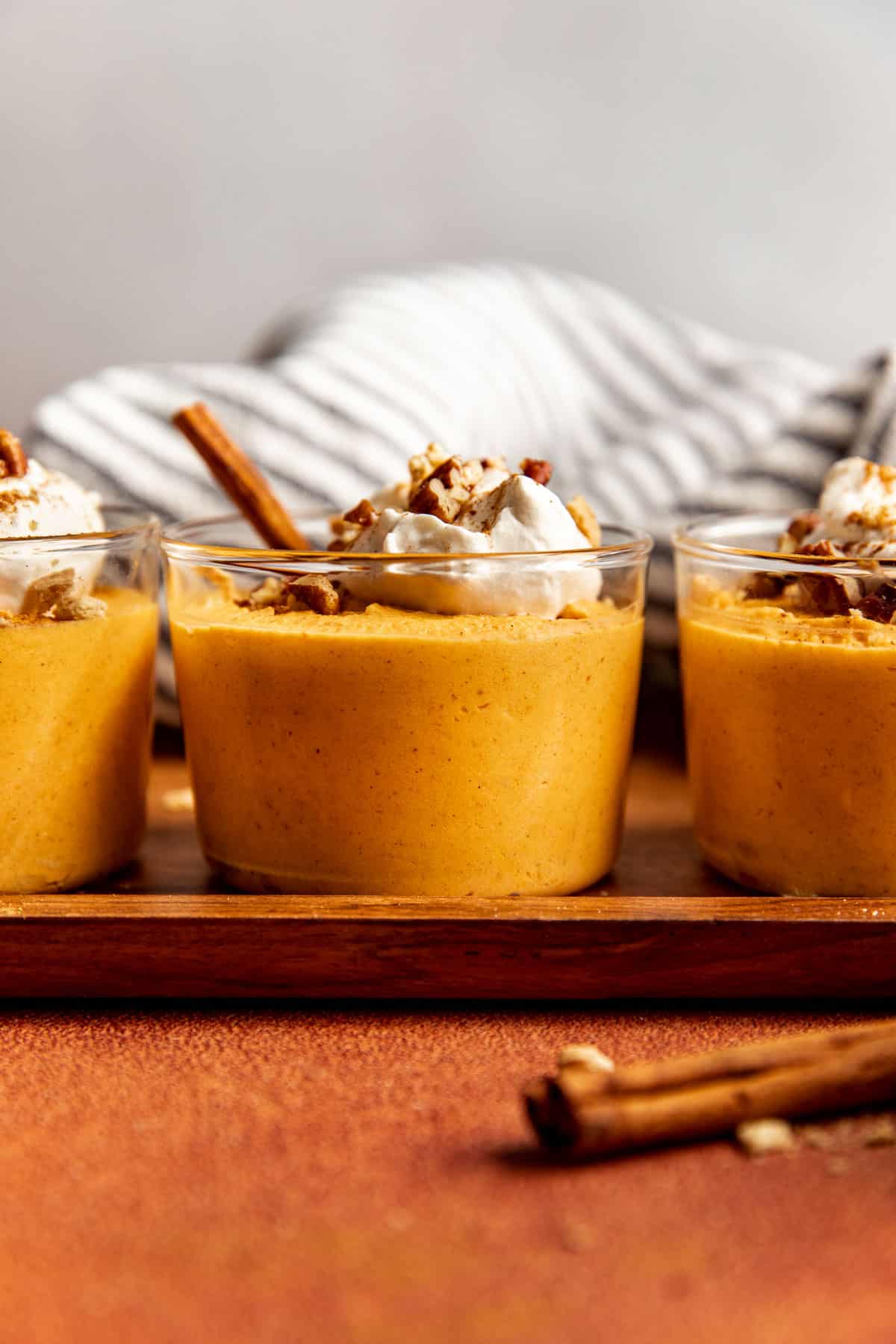 pumpkin mousse in glass containers with whipped cream and pecans on top. 