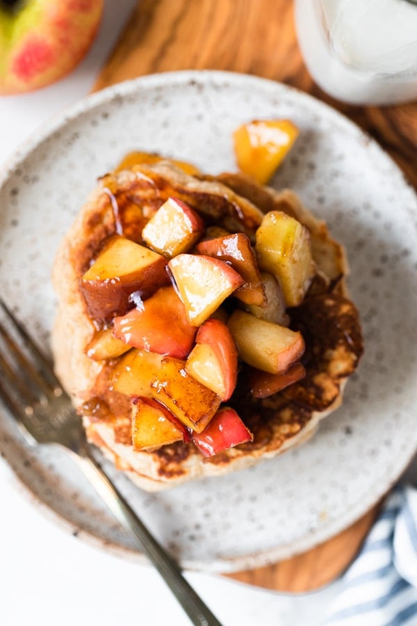 pancakes on a plate with syrup and apples on top