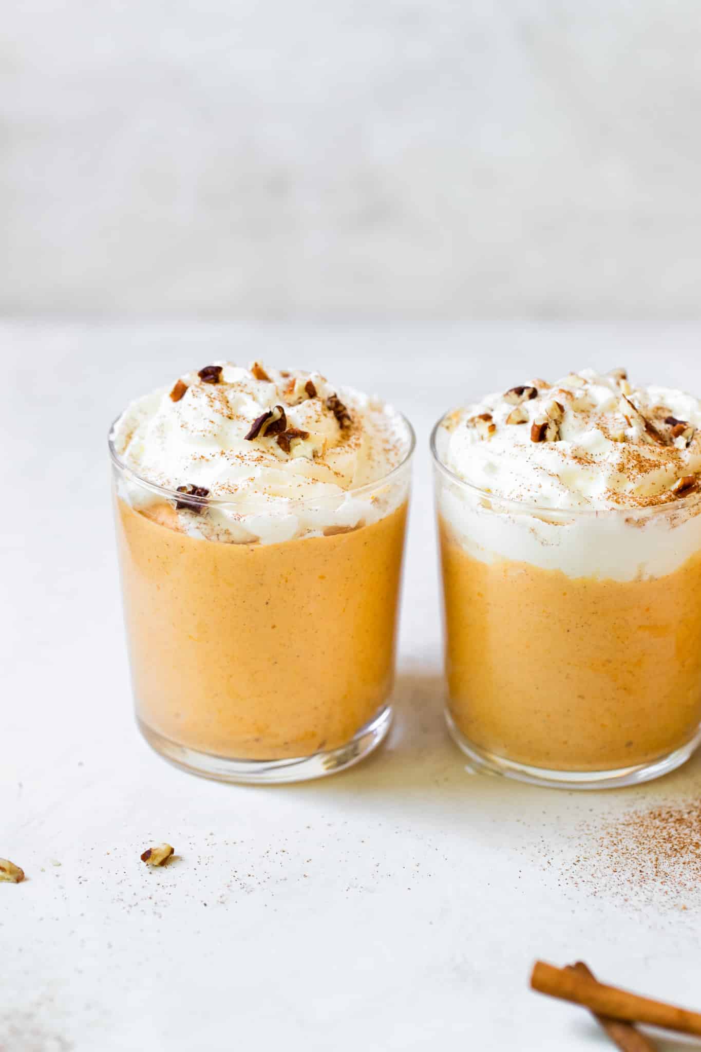 pumpkin mousse in a glass topped with whipped cream and pecans