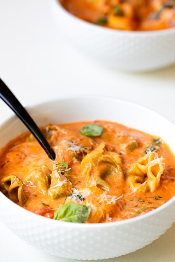 tomato soup with tortellini in a white bowl