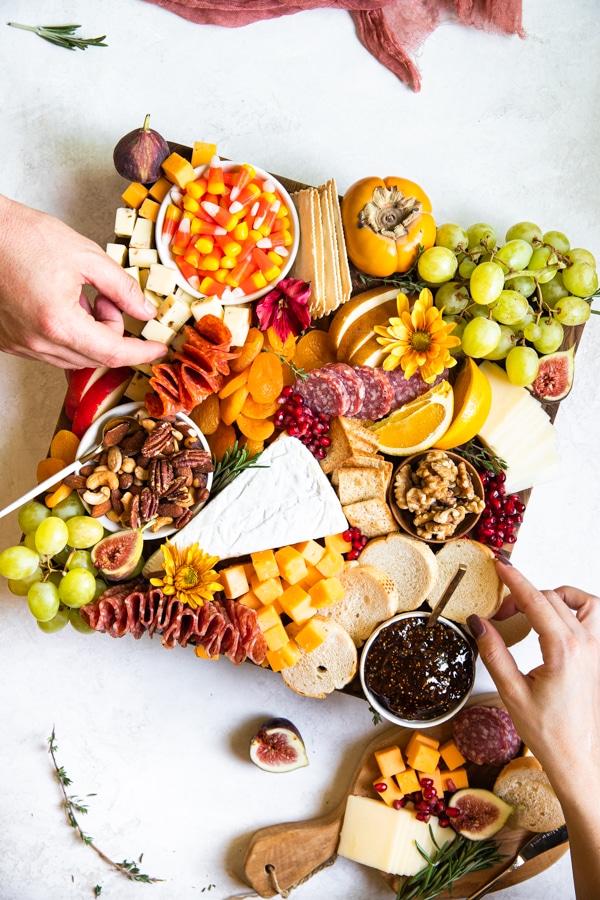 a charcuterie board filled with fruits, meats and cheese on a wood cutting board