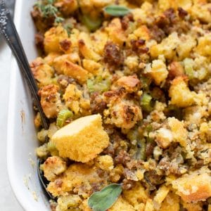 cornbread stuffing made with sausage and herbs in a white casserole dish