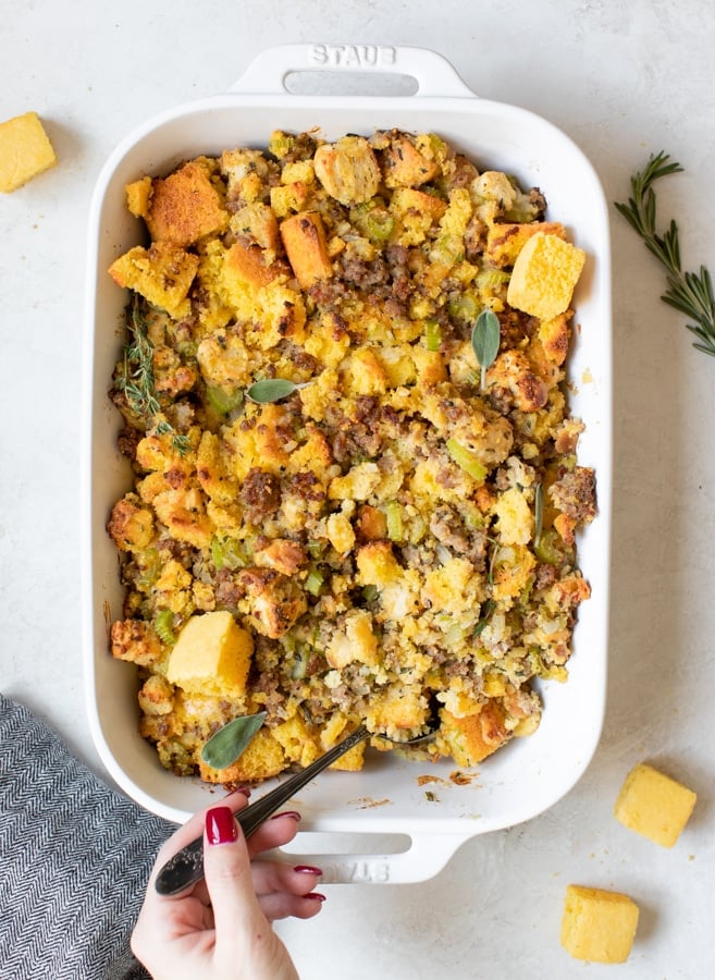 cornbread stuffing made with sausage and herbs in a white casserole dish