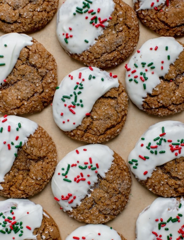 molasses cookies covered in sanding sugar on parchment paper dipped in white chocolate