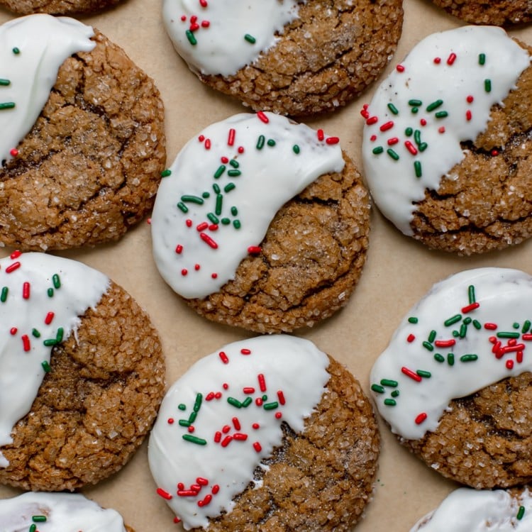 molasses cookies covered in sanding sugar on parchment paper dipped in white chocolate