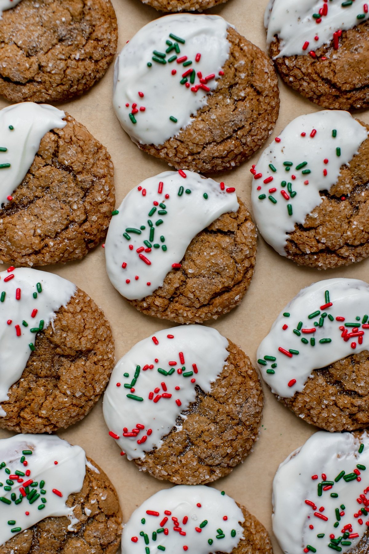 molasses cookies covered in sanding sugar on parchment paper dipped in white chocolate