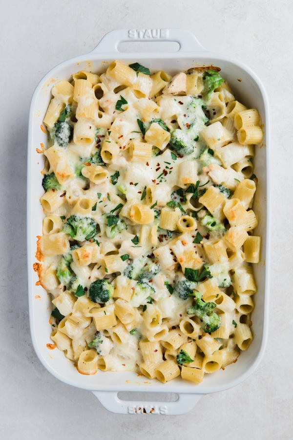 a casserole dish filled with pasta, cheese, broccoli and chicken